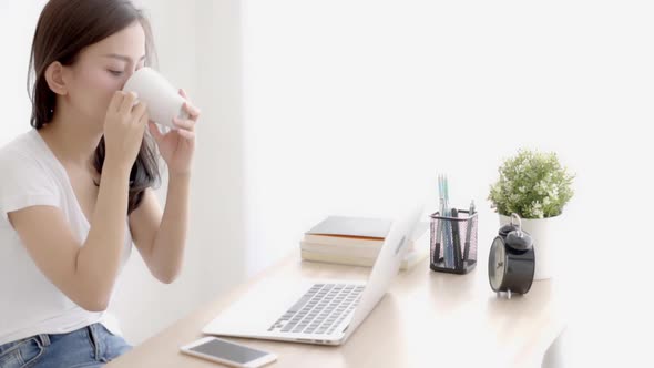 Beautiful young freelance asian woman smiling working and on laptop computer at desk office.