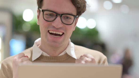 Close Up of Young Male Designer Celebrating Success on Laptop