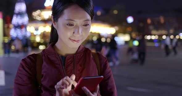 Woman use of mobile phone in city at night