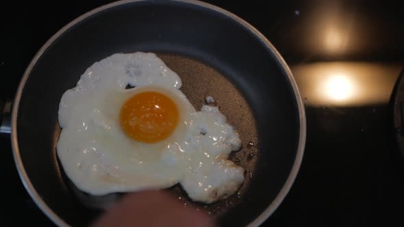 Frying Fresh Egg In A Skillet With A Fork - Sunny Side Up - overhead shot