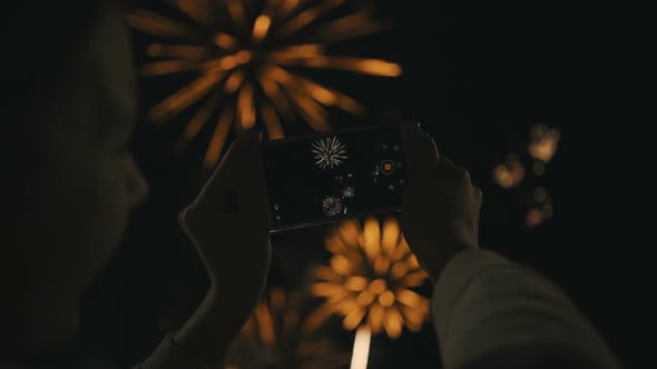 Silhouette of a Woman Photographing Fireworks at Night Sky