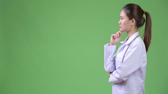 Profile View of Young Happy Beautiful Asian Woman Doctor Thinking
