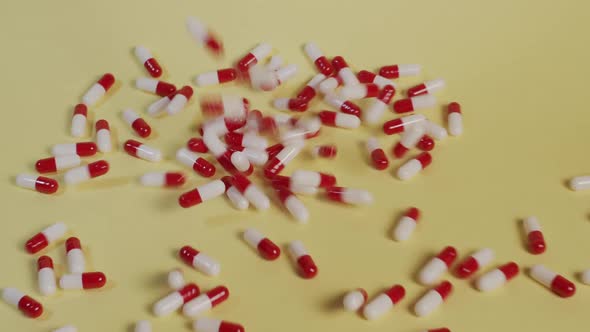 Slow motion high-angle medium shot as a handful of pills fall vertically.