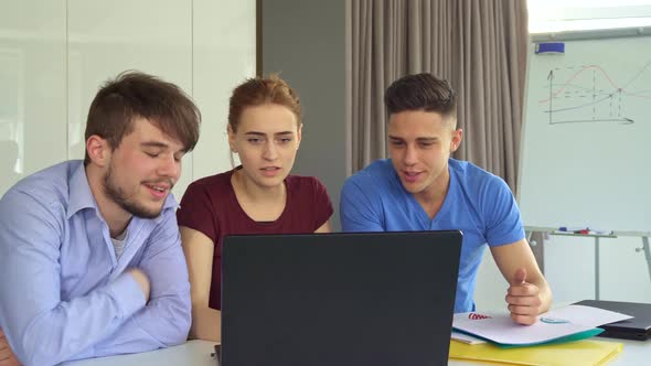 Young People Discuss Something on Laptop at the Office