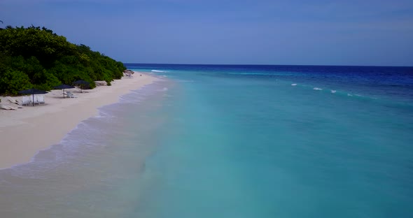 Wide birds eye travel shot of a sandy white paradise beach and aqua blue water background in colorfu