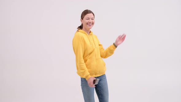 Happy young woman is dancing and smiling in a light screen background. The positive