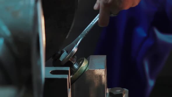 Industrial Worker Is Tightening Screws with a Wrench at a Factory. Metalworking CNC Milling Machine