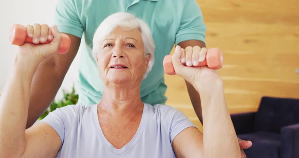 Video of midsection of african american male physiotherapist exercising with caucasian senior woman