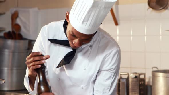 Chef sprinkling pepper on a meal