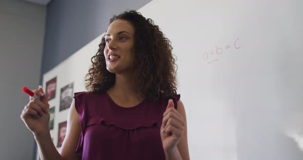 Video of happy caucasian female teacher standing in classroom and explaining lesson