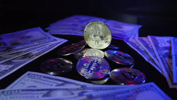 Shiny bitcoin rotating and reflecting light on dark surface with BTC coins and dollars.