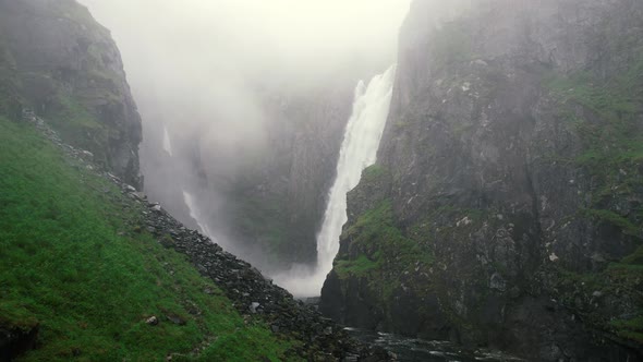 Misty View Though Ravine Of Falling Voringsfossen Waterfall. Aerial Dolly Back