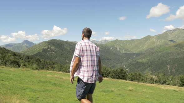 Back and Side View of Young Man Hiking in Mountain Outdoor Nature Scenery During Sunny Summer Day