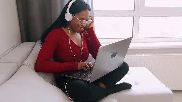 Young African Woman in Headphones with Laptop Working at Home