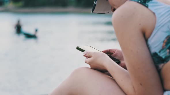 Young Woman Uses a Smartphone on the Beach