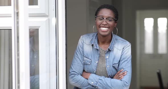 Confident woman leaning in door of her home, laughing