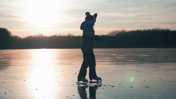 Cute Little Girl Is Going Skate Outdoors at Sunset. A Schoolgirl Enjoying Ice Skating at Frozen Lake