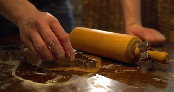 Male hand cutting the flattened gingerbread dough with cutting form. Close up