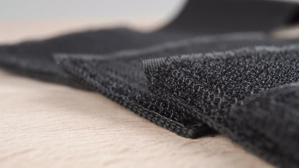 Black textured Velcro hooks on fabric tapes. Close up on a wooden surface