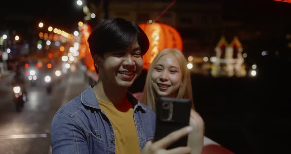 Young Asian couple travel make a video live streaming on social network by smartphone.