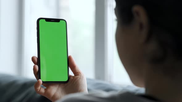 A Young Woman Uses A Smartphone with a Green Screen, Holds a Phone with a Chromakey for Graphics