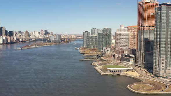 A high angle view looking north over the East River on a sunny day. The drone camera dolly out and p
