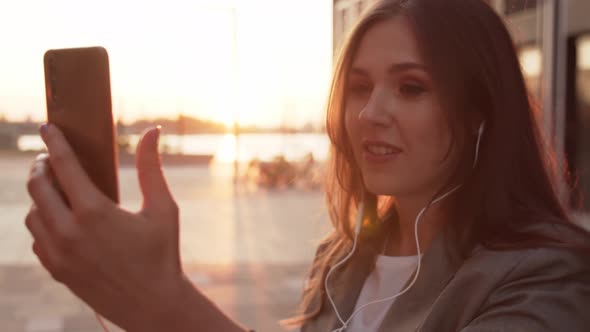 Young attractive business woman sitting outdoor on the bench and using smartphone.