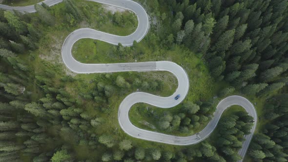 Town down aerial tracking view of sports car driving over winding German roads