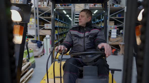 Portrait of Confident Warehouse Loader Operator Driving Autoloader Waving Greeting Colleague in