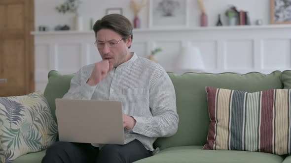 Man with Laptop Coughing on Sofa