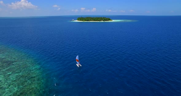 Aerial drone view of a man and woman sailing on a boat to a tropical island