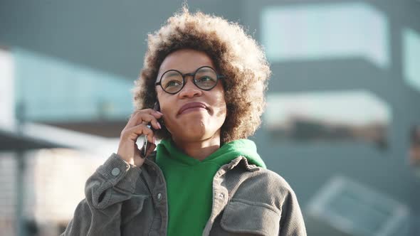 Cheerful adult African woman wearing casual clothes talking by phone