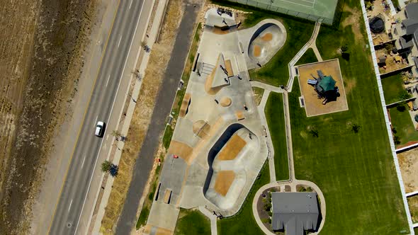Ascending aerial, bird's eye view of an urban skate park in summer