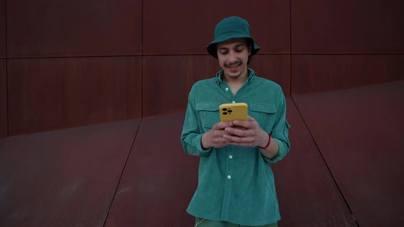 Happy Guy Typing Messages on Smartphone Outdoors