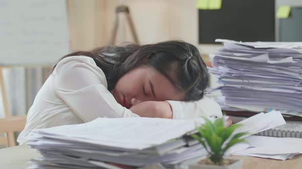 Close Up Of Tired Asian Woman Sleeping Due To Working Hard With Documents At The Office