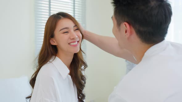 Asian new marriage couple sit on bed and look at each other with love.