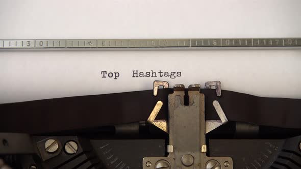 Typing phrase Top Hashtags on retro typewriter. Close up.