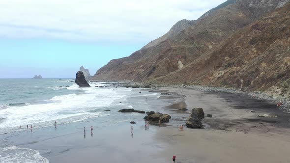 Tenerife, people on the wild Benijo beach with black volcanic sand. Big waves of the Atlantic ocean