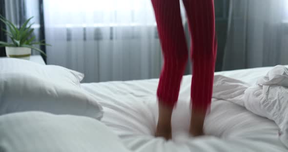 Unrecognizable girl having fun jumps bed