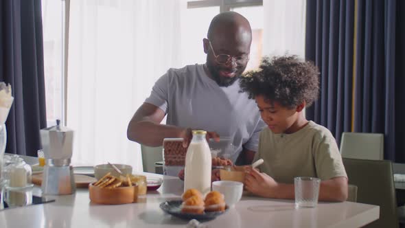 African American Boy Having Breakfast with Dad at Home