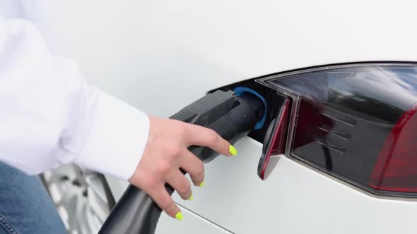 Close Up View of Woman's Hands Disconnect Power Supplier to Electric Car