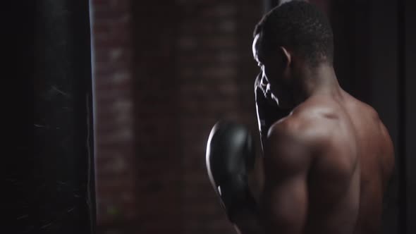 Black Young Man Boxer Training in the Gym  Punching a Punching Bag