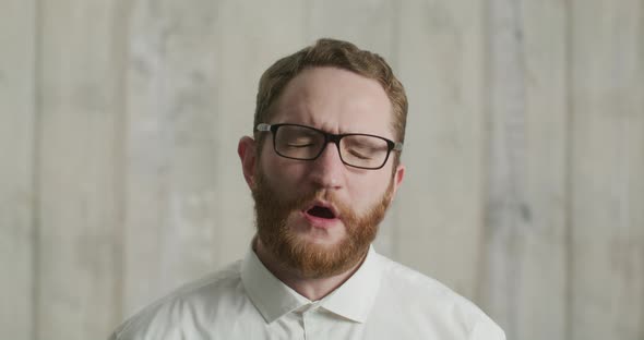 Portrait of an Attractive Man Yawning in a White Shirt