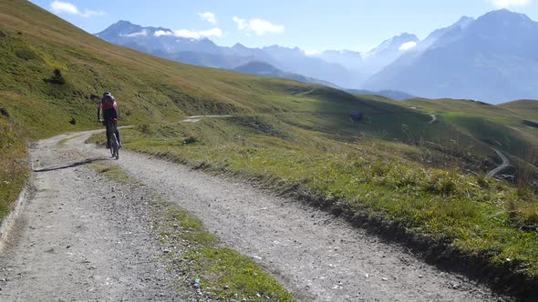 A man mountain biking on a European mountainside biking trail.