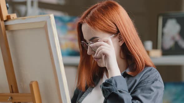 Caucasian Woman Artist Girl Painter with Red Hair Put on Eyeglasses Wearing Glasses Start Art Work