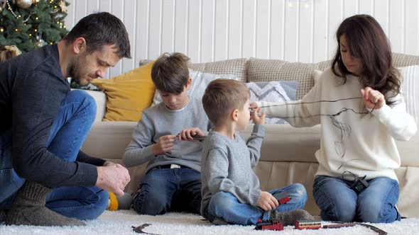 Family is Building a Railroad Track at Home Together in Christmas Eve