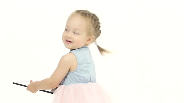 Baby Is Holding a Laptop and Whirls in a White Studio. White Background Slow Motion