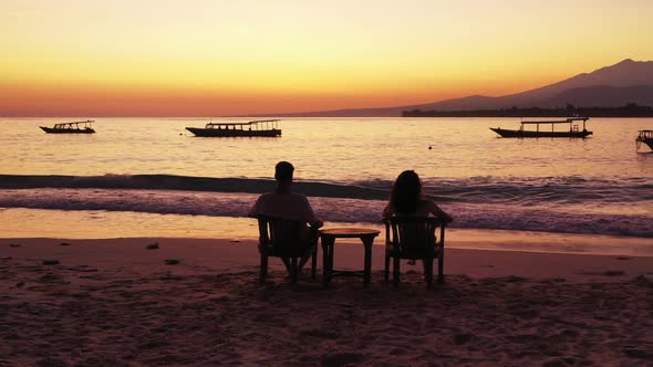 Young couple sunbathe on idyllic coastline beach vacation by blue lagoon and white sand background o