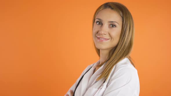 Young Beautiful Female Doctor Smiling Wide, Turning Against Camera Slowly. Studio Shot