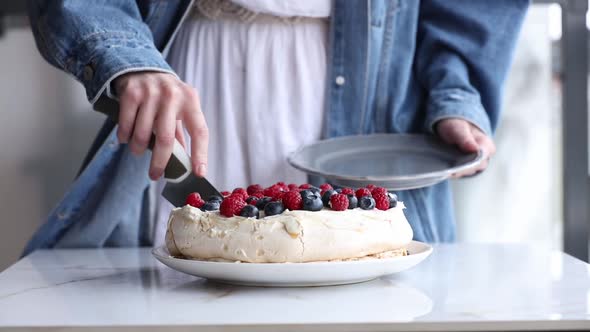 woman slice meringue cake on the table